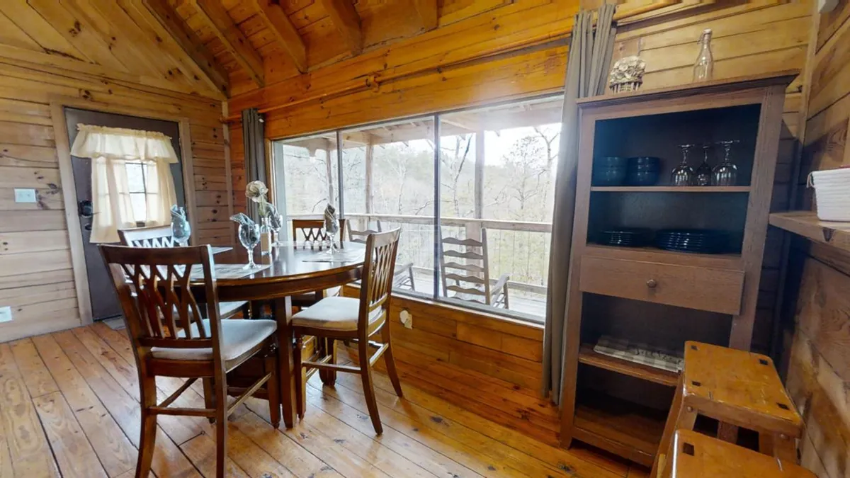 A charming interior dining nook featuring a wooden table positioned by a window with inspiring natural views. The ambiance is set for intimate candlelit dinners, with touches of rustic charm that enhance the romantic mood.