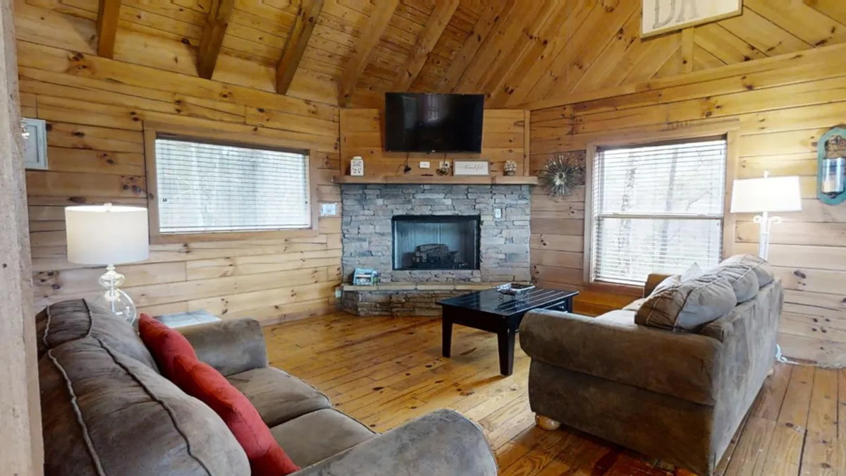 A cozy living area with a stone fireplace, wooden beams, comfortable sofas, and a coffee table. The space feels inviting and is ideal for relaxing, socializing, or planning outings with the provided high-speed WiFi.